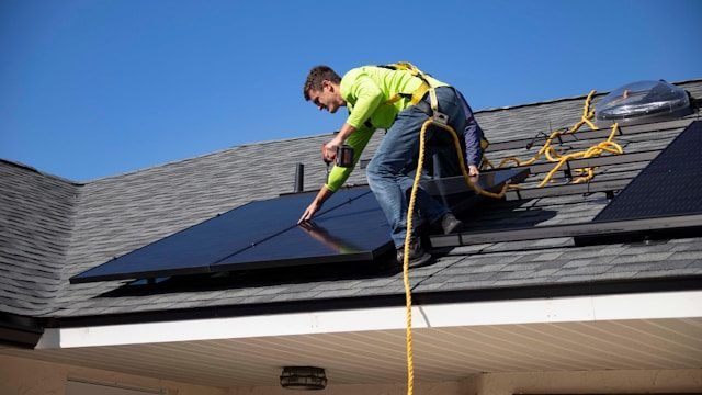 Worker installing solar panels on a roof